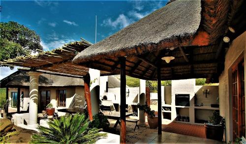 a straw roofed patio with white chairs and tables at Graceland Eco Retreat in Magoebaskloof