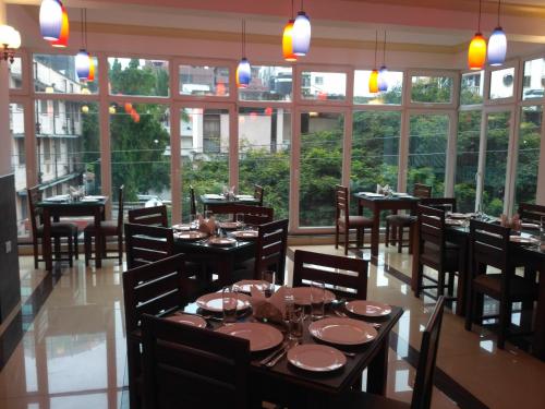 a dining room with tables and chairs and windows at Chelsea Hotel in Dar es Salaam