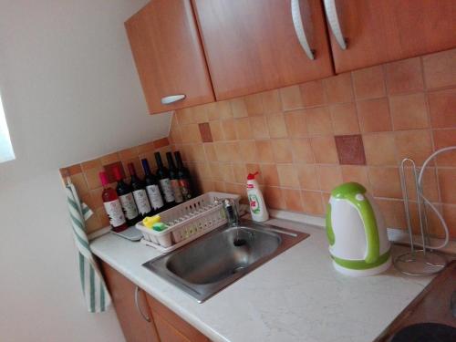 a kitchen counter with a sink and bottles of wine at Ottó Panzió Villány in Villány