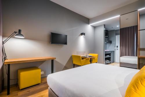 a hotel room with a bed and a desk and a tv at Apartamentos Turisticos Paraiso in Funchal