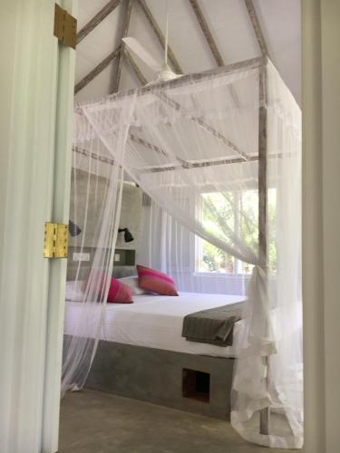 a bed with a canopy in a room with a window at Good Vibes Villas in Unawatuna