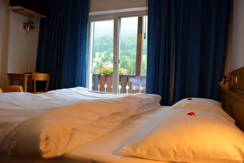 Cama en habitación de hotel con ventana en Hotel Val Di Fassa, en Soraga