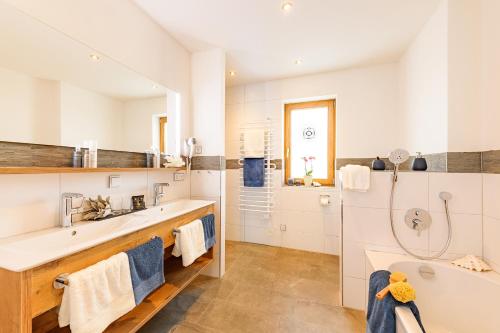 a white bathroom with a tub and a sink at Casatina Ferienwohnungen in Oberstdorf