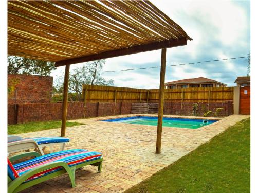 uma pérgola de madeira com duas cadeiras e uma piscina em Sundune Guest House em Colchester