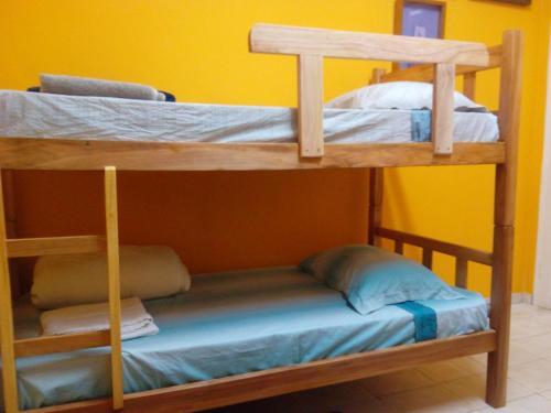 2 Etagenbetten in einem Zimmer mit gelber Wand in der Unterkunft Mini Hostel Fine Art in Vitória da Conquista