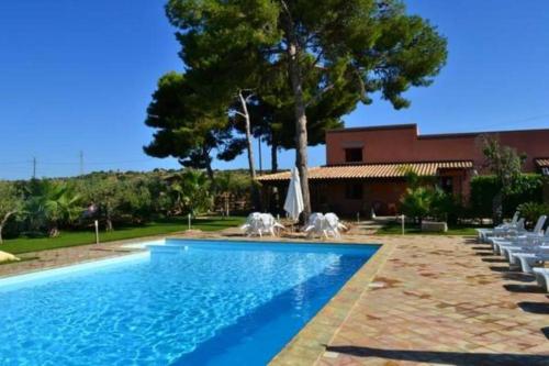 a swimming pool with chairs and a house at Holiday Menfi | Casale Abate in Menfi