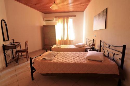 1 dormitorio con 2 camas, mesa y ventana en Nianthi Apartments, en Mithimna