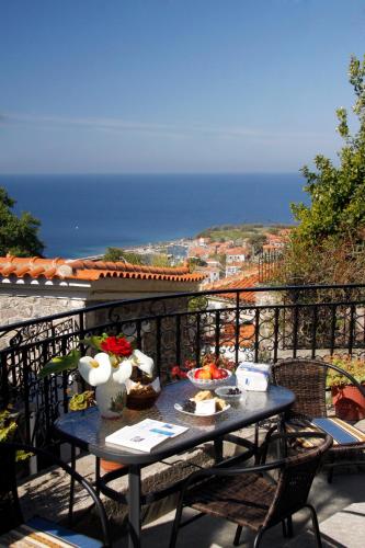a table on a balcony with a view of the ocean at Nianthi Apartments in Mithymna