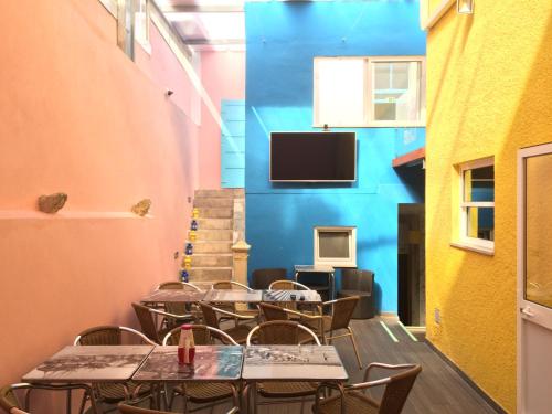 フィゲイラ・ダ・フォズにあるMeeting Hostelのテーブルと椅子、壁掛けテレビのあるレストラン
