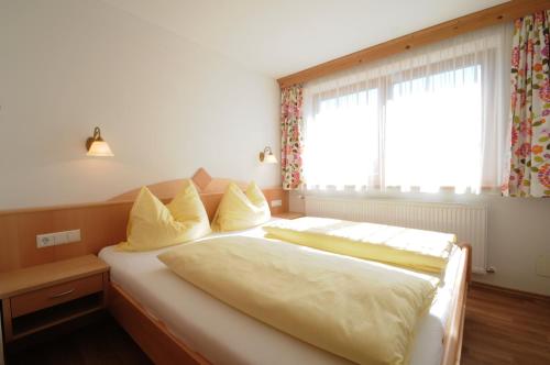 een slaapkamer met een bed met gele kussens en een raam bij Ferienhaus Hubertus - PRECHTLHOF in Flachau