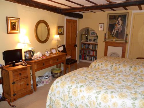 a bedroom with a bed and a desk with a television at Denmark House in Long Melford