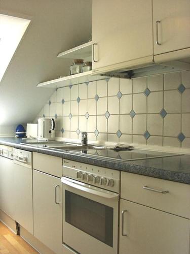 eine Küche mit weißen Geräten und blauen Fliesen in der Unterkunft Konstanz-Wallhausen in Konstanz
