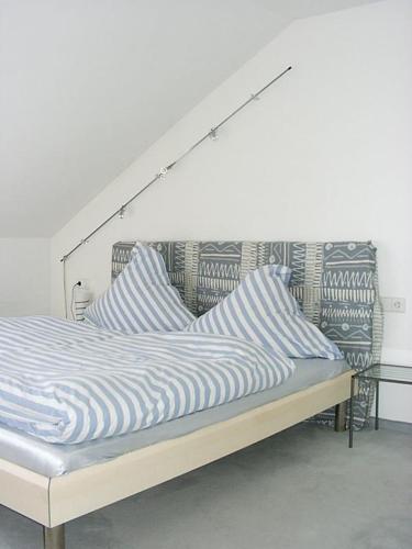 Bett mit weißer und blauer gestreifter Bettwäsche und Kissen in der Unterkunft Konstanz-Wallhausen in Konstanz