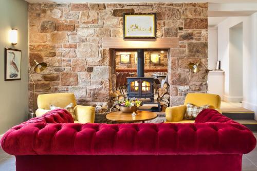 a red couch in a living room with a stone wall at Pentonbridge Inn - Restaurant with Rooms in Carlisle