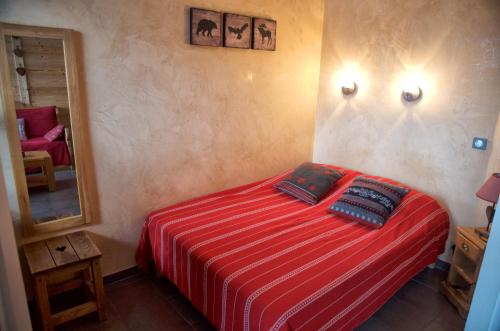 - une chambre avec un lit doté d'une couverture rouge et d'un miroir dans l'établissement Chamois, à Chamonix-Mont-Blanc