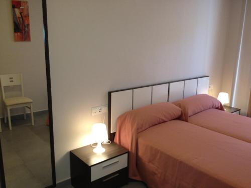 1 dormitorio con 2 camas y mesita de noche con lámpara en Pension La Puntica en Lo Pagán