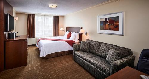 a hotel room with a bed and a couch at Best Western Plus Guildwood Inn in Sarnia