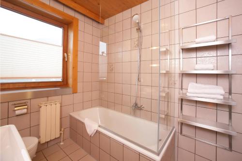 a bathroom with a tub and a toilet and a window at Apartments Obernosterer - Großglockner in Kaprun