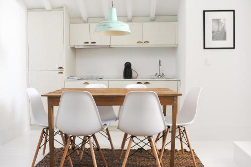 cocina con mesa de madera y sillas blancas en Mo House en Oporto