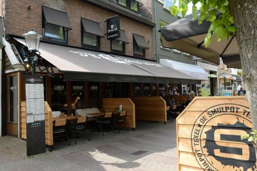 a restaurant with tables and chairs in front of a building at Boutique Hotel De Smulpot in Den Burg