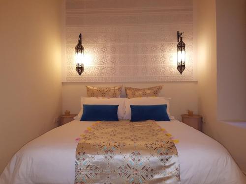 a bedroom with a large white bed with blue pillows at Dar Andamaure in Marrakech