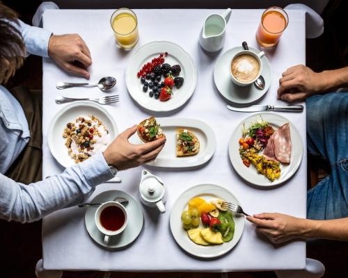 eine Gruppe von Menschen sitzt um einen Tisch herum und isst in der Unterkunft Room Mate Alicia, Madrid in Madrid