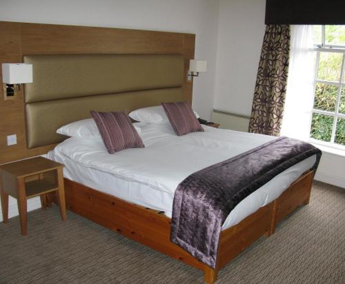 a bedroom with a large bed with a wooden headboard at Guy's Thatched Hamlet in Barton