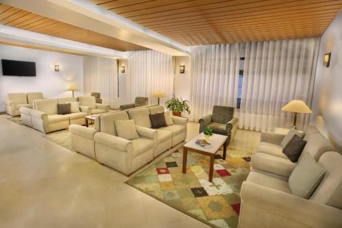 a living room with couches and chairs and a tv at Hotel Santo António de Fátima in Fátima