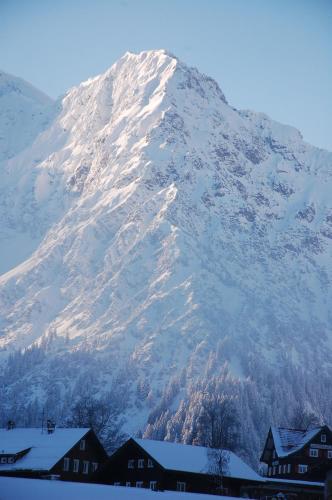 a snow covered mountain with houses in front of it at Herzen´s Landhaus in Hirschegg