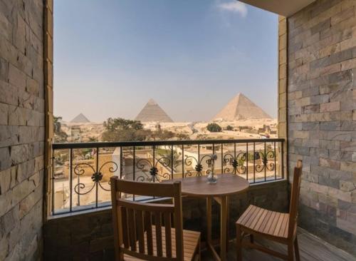 a balcony with a table and chairs and the pyramids at Pyramids View Inn in Cairo