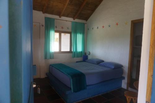 a bedroom with a bed with blue sheets and a window at Hosteria Tsafiki in Puerto López