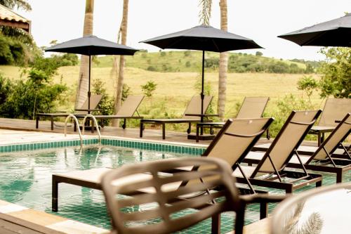 a group of chairs and umbrellas next to a swimming pool at Pousada Santa Thereza in Serra Negra