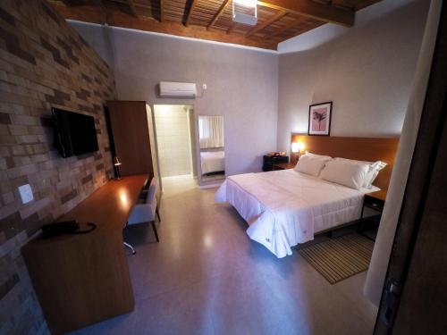 a hotel room with a bed and a television at Pousada Santa Thereza in Serra Negra