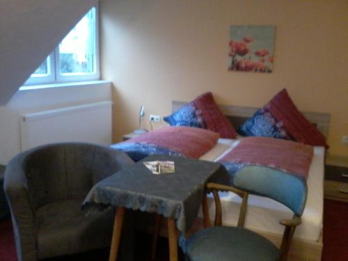 a bedroom with two beds and a chair and a table at Waldpension zum Felsenkeller in Lichtenfels-Sachsenberg