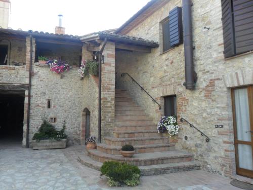 a stone building with stairs and flowers on it at Agriturismo Piandellerose in Avigliano