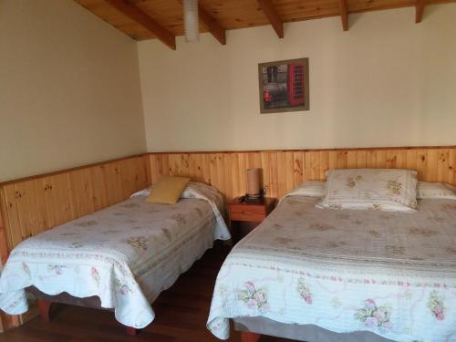 two beds in a room with wooden walls at Hostal Balmaceda La Serena in La Serena