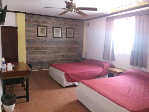 a bedroom with two beds and a table and a ceiling fan at Easy Inn Hotel in Belize City