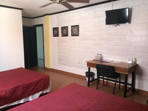 a bedroom with a desk and a bed and a tv on a wall at Easy Inn Hotel in Belize City