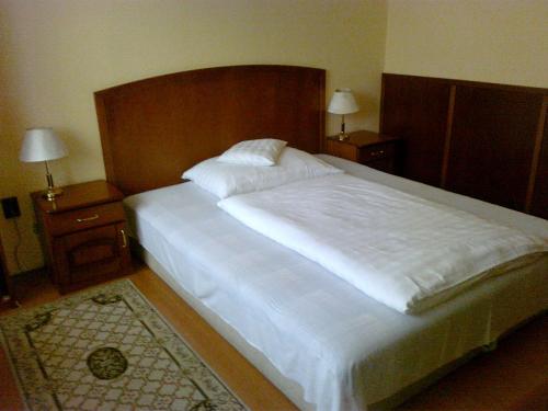 a bedroom with a large white bed with two night stands at Szieszta Panzió in Sárvár