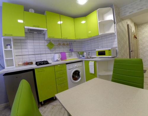 カリーニングラードにあるCozy apartment on Сhernyahovskogo 78のキッチン(ライムグリーンのキャビネット、テーブル、椅子付)
