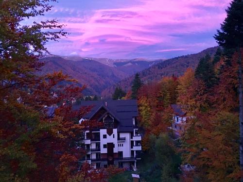 une maison au milieu d'une vallée avec des arbres dans l'établissement Apartament Stanca Piticului, à Sinaia