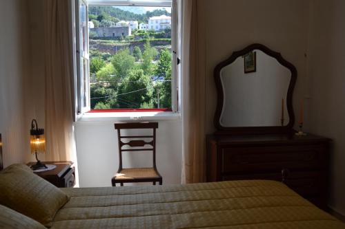 a bedroom with a bed and a mirror and a window at Casa da Ponte do Arrocho in Loriga