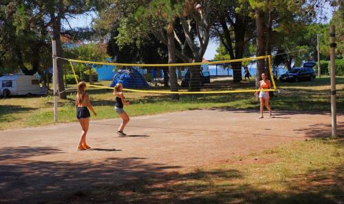 three girls playing a game of volleyball in a park at SunFlower Camping Savudrija in Savudrija