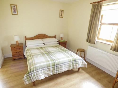 a bedroom with a bed with a plaid blanket and a window at Maison de Kilbride Finney Clonbur Mayo in Clonbur