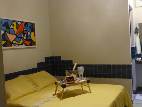 a yellow bed with a table in a room at Pousada das Bromélias in Porto De Galinhas