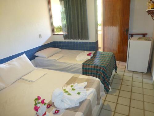 a room with two beds and a refrigerator at Pousada das Bromélias in Porto De Galinhas