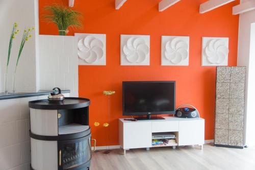 a living room with a tv and orange wall at Ferienwohnung "schöner Wohnen" in Westerstede