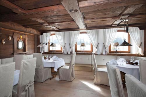 a restaurant with white tables and chairs and windows at Relais & Châteaux Gut Steinbach Hotel Chalets SPA in Reit im Winkl