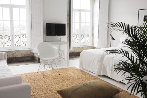 a white bedroom with a white bed and a chair at Mo House in Porto