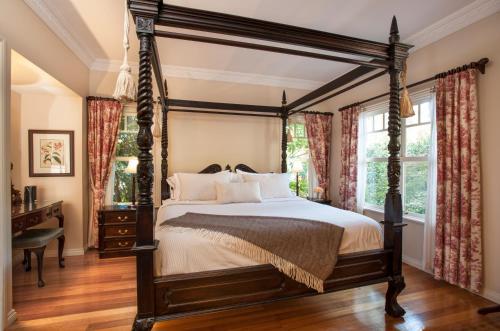 - une chambre décorée avec un lit à baldaquin et des fenêtres dans l'établissement Fern Falls Cottages - Garden Cottage, à Mont Dandenong